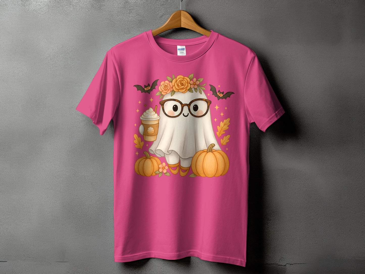 Pink t-shirt with a ghost wearing glasses and holding a coffee, surrounded by pumpkins.