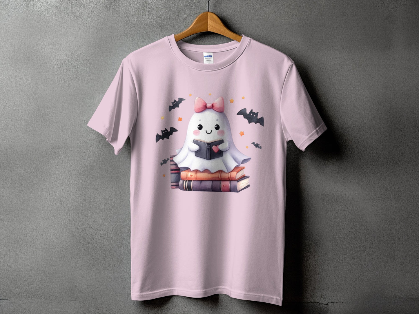 Pink t-shirt with a cute ghost reading a book surrounded by bats and stars.