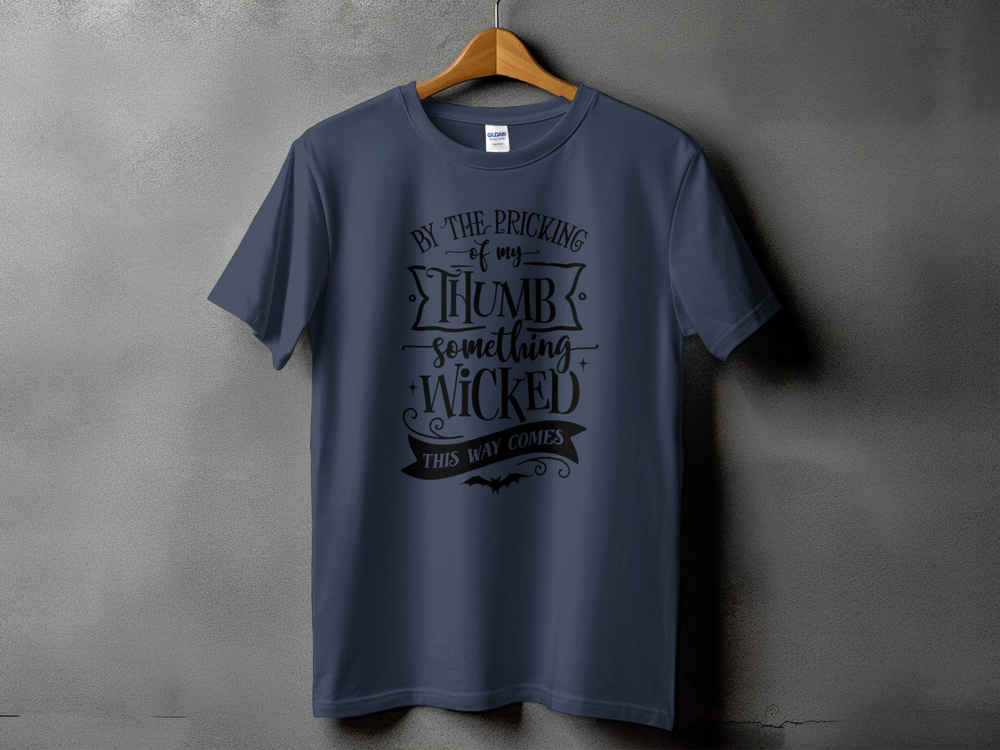 Dark blue t-shirt with black text that reads "By the pricking of my thumb something wicked this way comes".