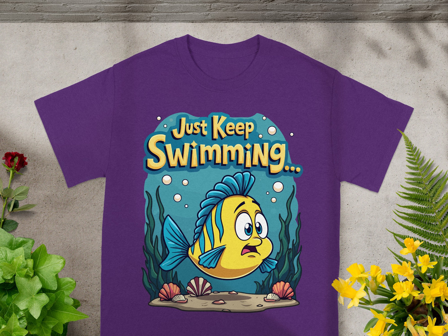Purple t-shirt with cartoon fish and text "Just Keep Swimming...".