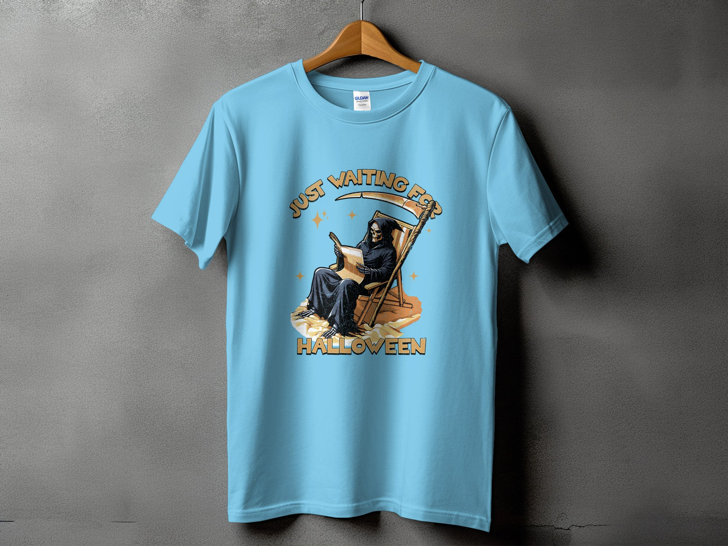 Grim reaper in a deck chair reading on a t-shirt that says "Just Waiting for Halloween".