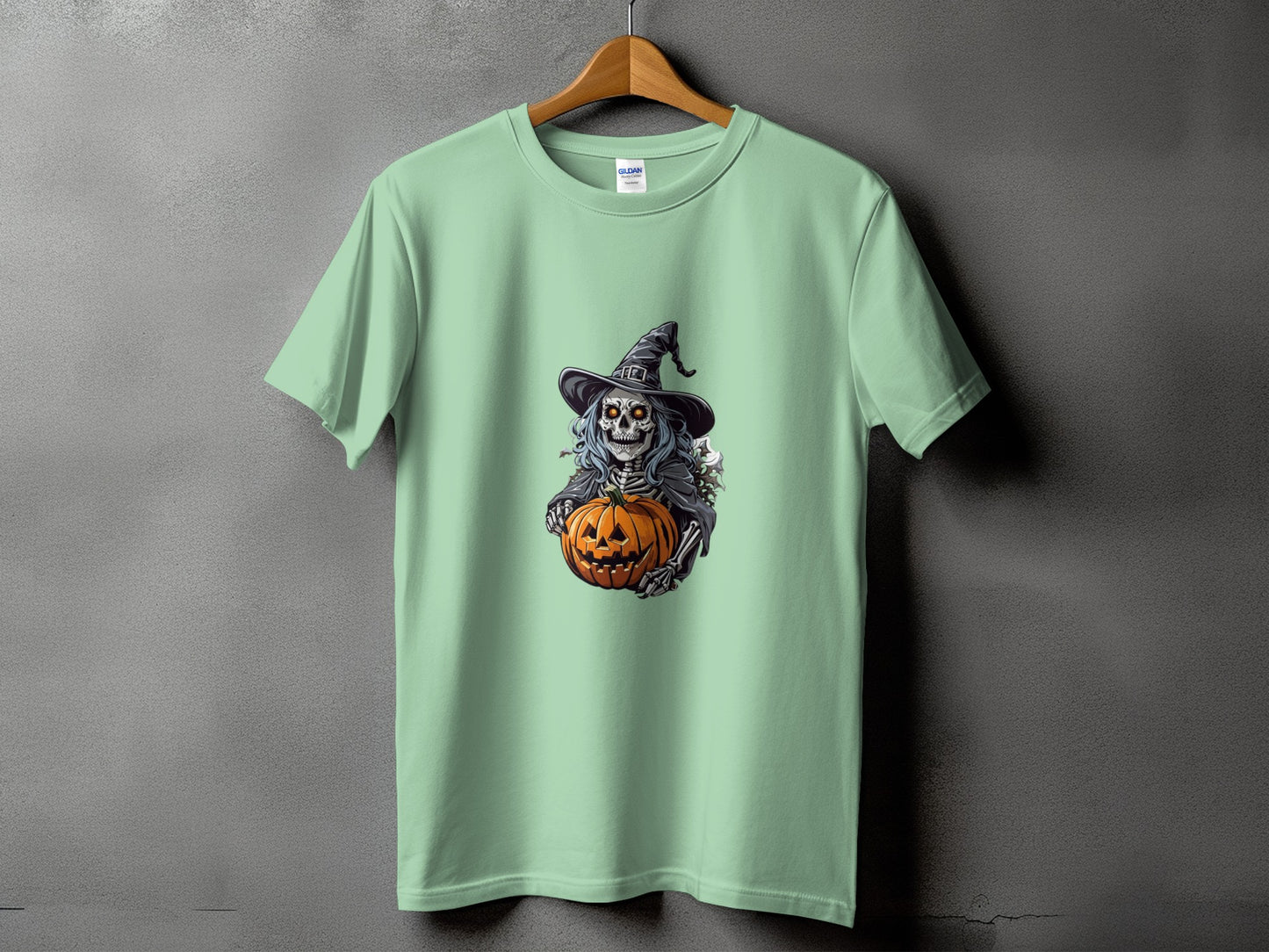 Light green t-shirt with a skeleton witch holding a jack-o'-lantern graphic.