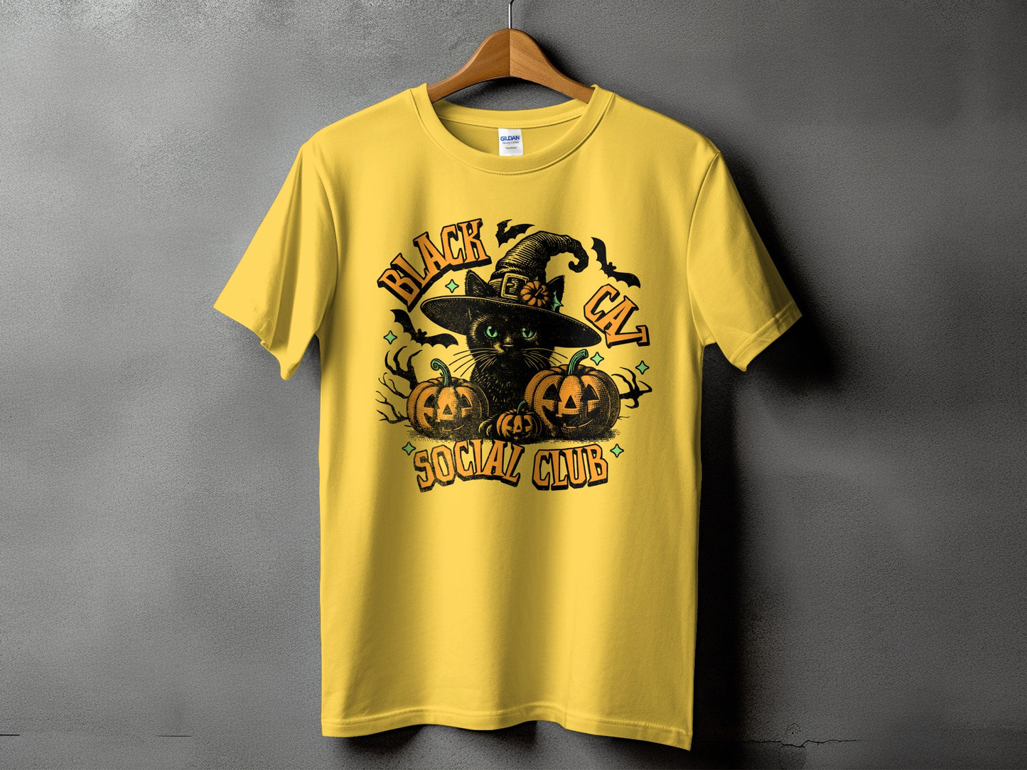 Yellow t-shirt with black cat, witch hat, pumpkins, bats, and text "BLACK CAT SOCIAL CLUB".