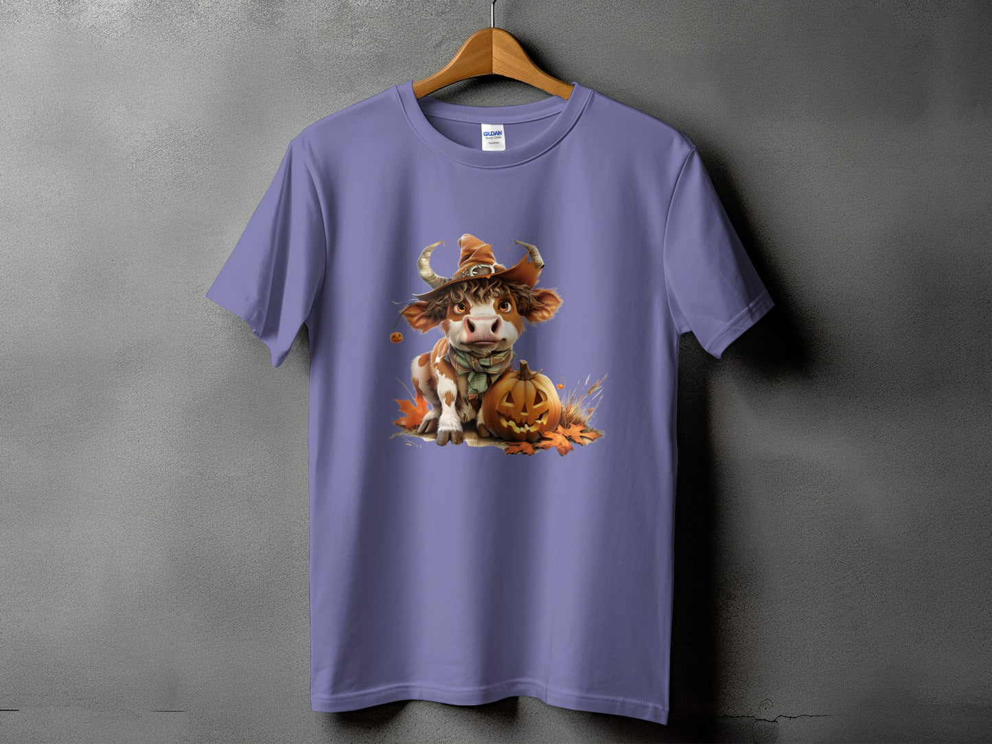 Cute cow with witch hat and pumpkin design on a purple t-shirt.