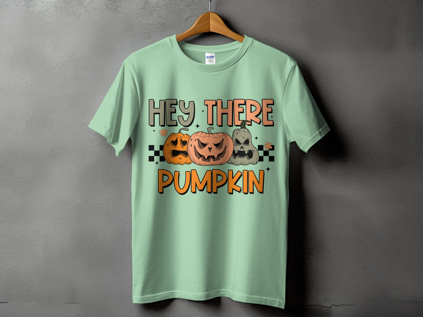 Light green t-shirt with "Hey There Pumpkin" and three carved pumpkins.