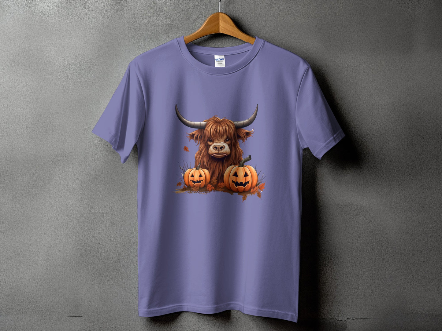 Highland cow with pumpkins and autumn leaves graphic on a purple t-shirt.
