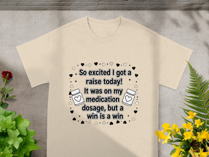 Cream t-shirt with "So excited I got a raise today! It was on my medication dosage, but a win is a win" text.