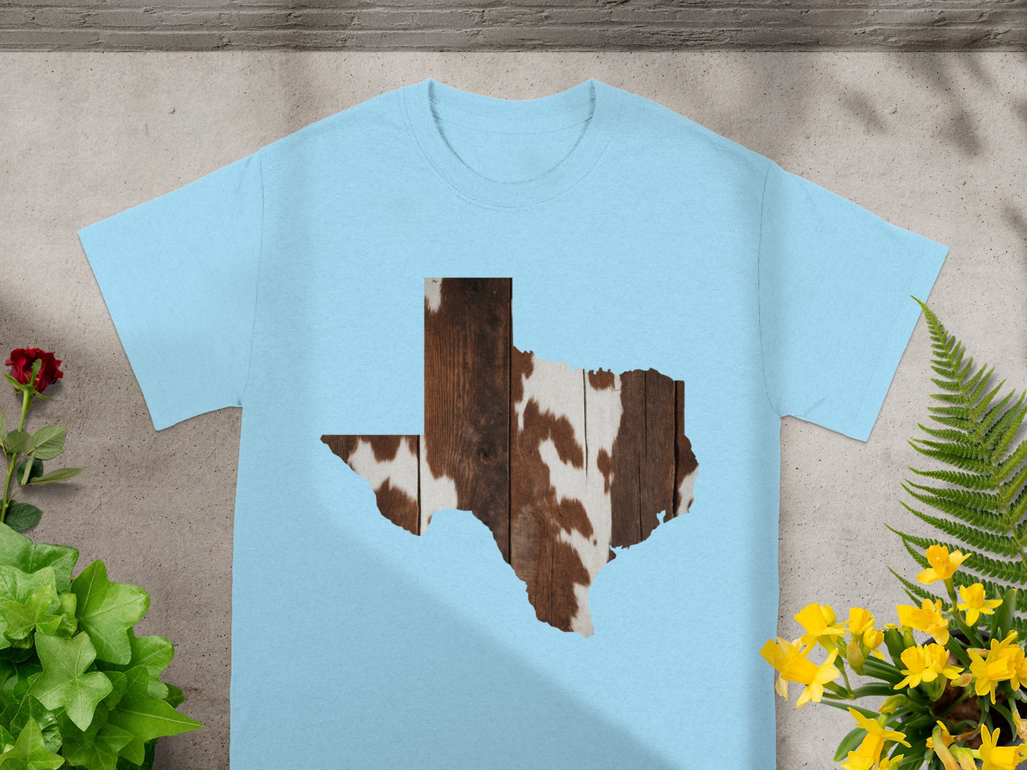 Light blue t-shirt with Texas shape graphic of wood and cowhide texture.
