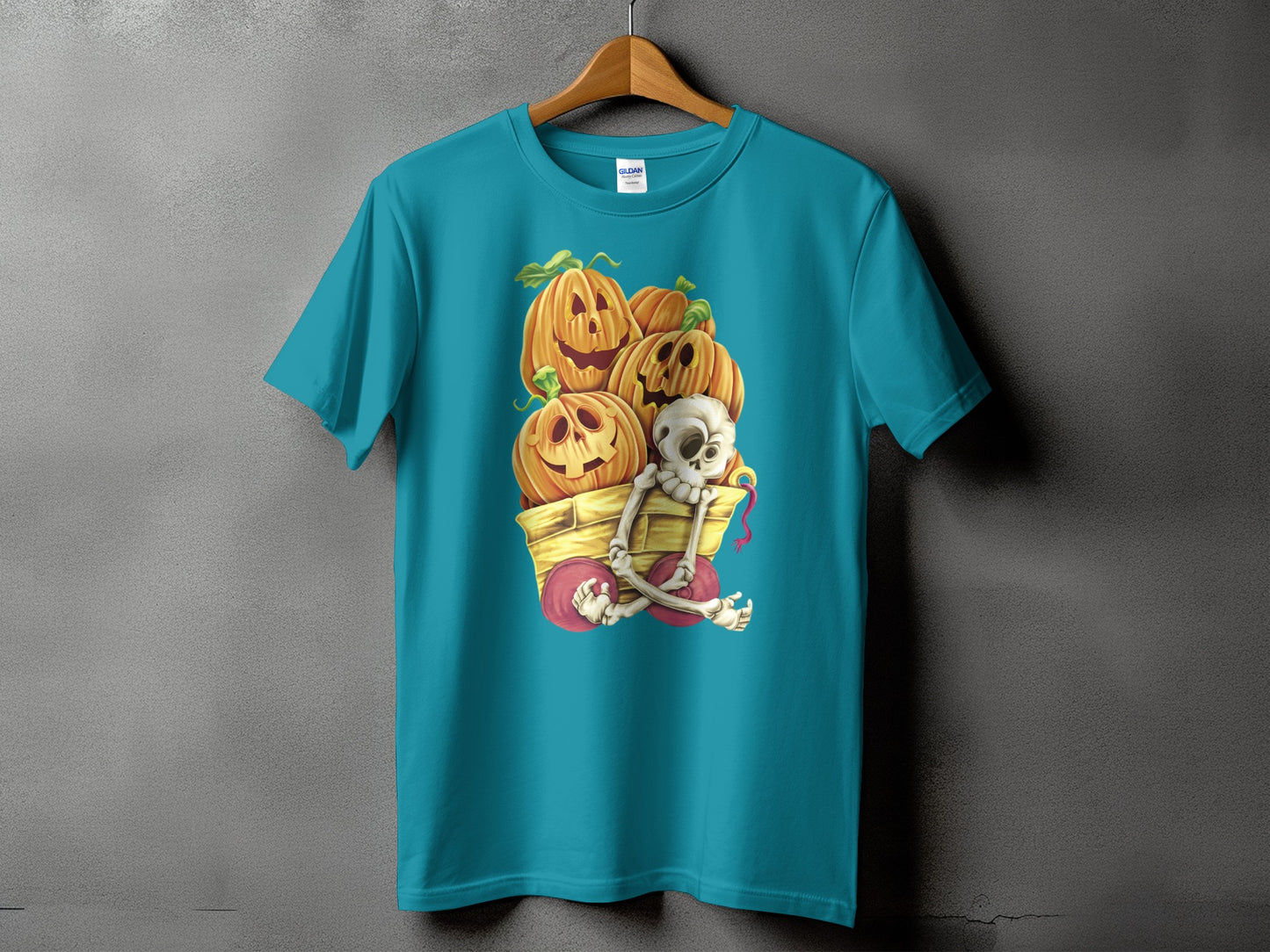 Teal t-shirt with Halloween graphic of a skeleton in a wagon full of jack-o'-lanterns.