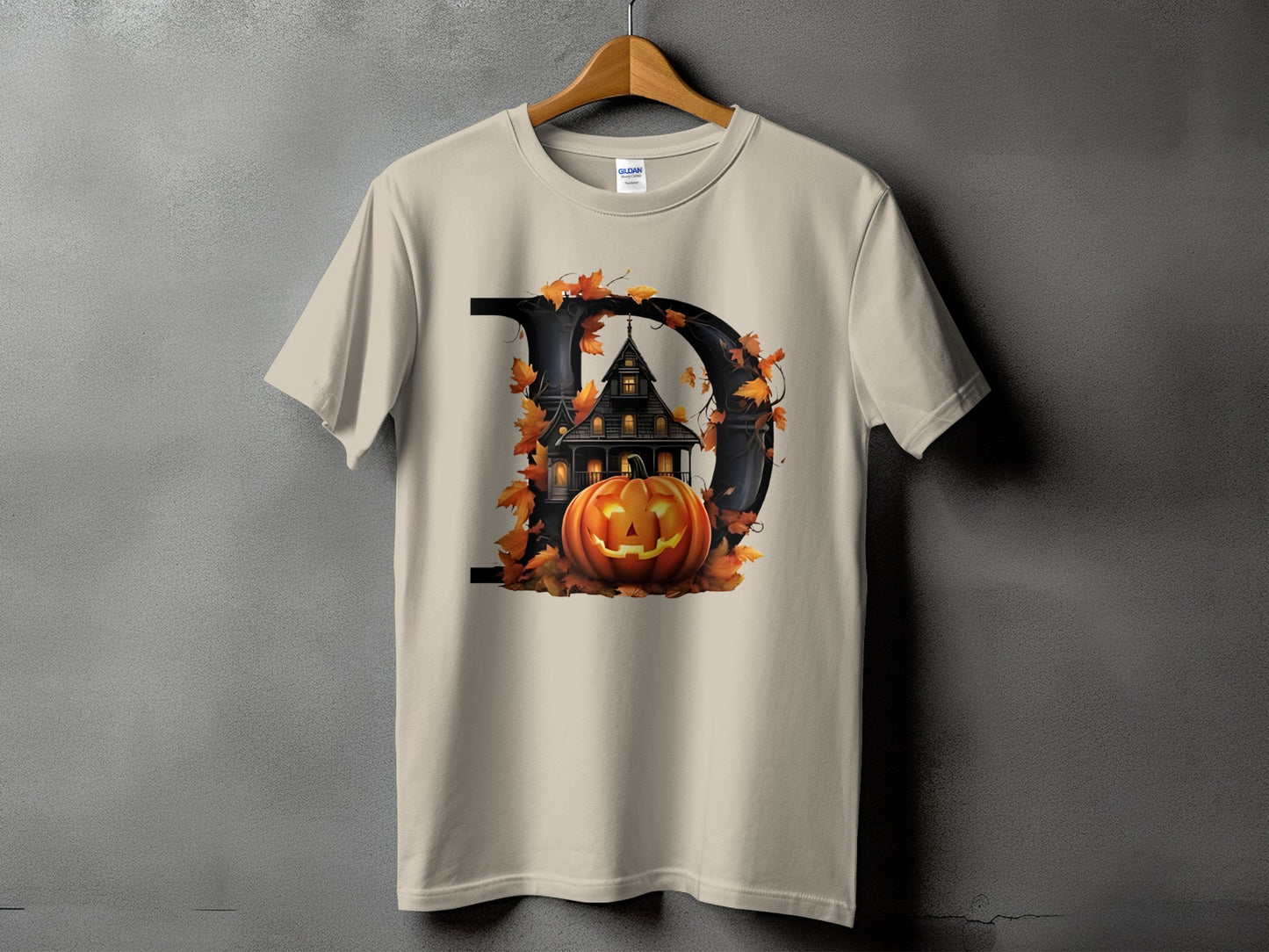 T-shirt with large black letter D, haunted house, pumpkin, and autumn leaves.