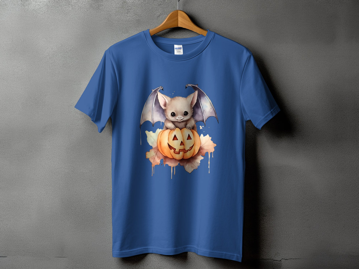 Blue t-shirt with cute bat sitting on a carved pumpkin with autumn leaves.