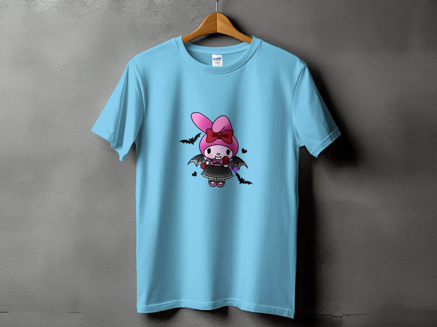 Light blue t-shirt with a cartoon character design featuring a pink bunny wearing a bat costume.