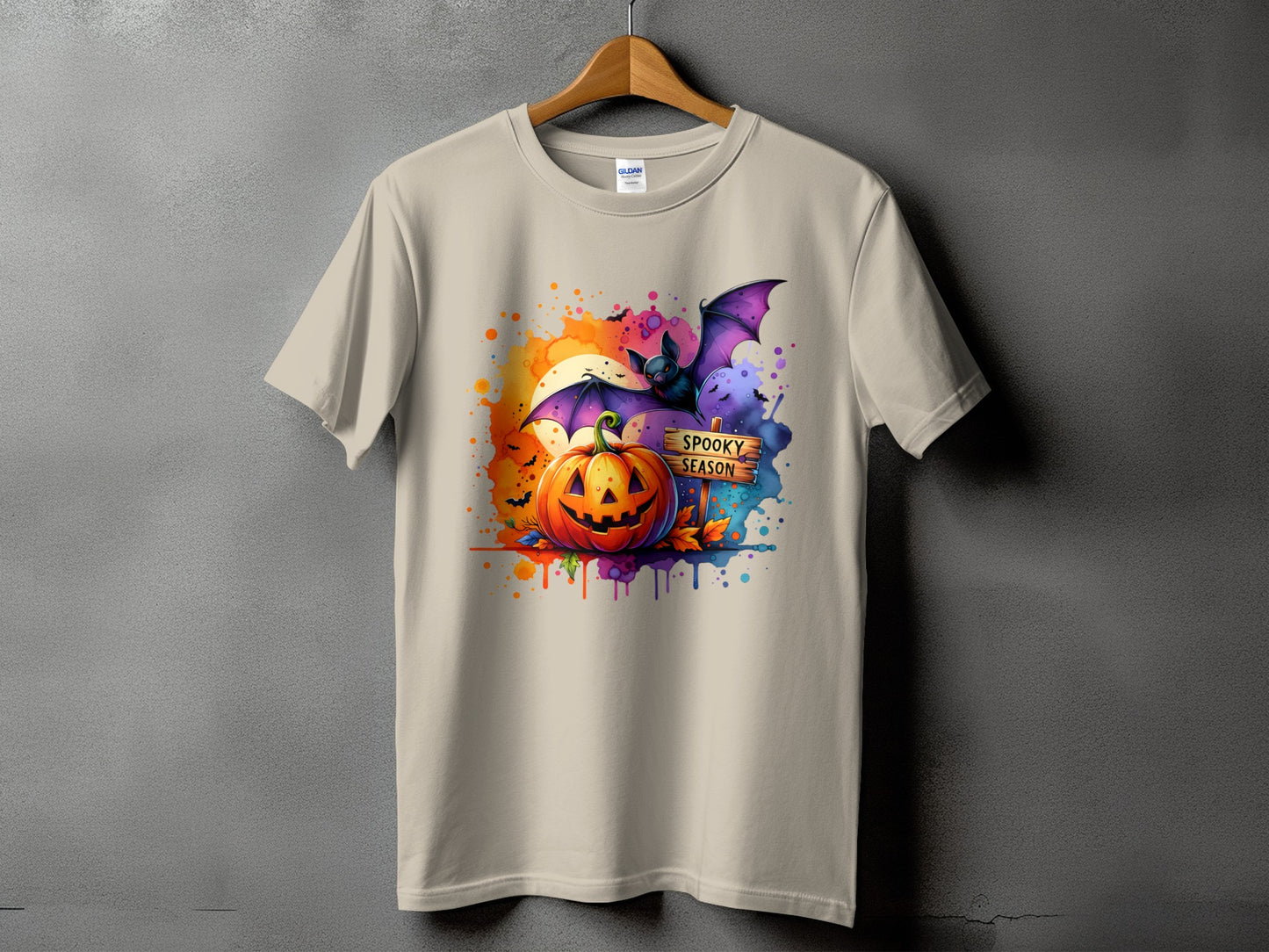 Light beige t-shirt with a Halloween graphic of a pumpkin, bat, and a "Spooky Season" sign.