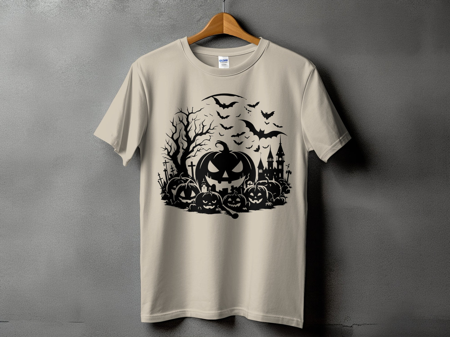 Halloween graphic on a tan t-shirt with pumpkins, bats, and a castle.