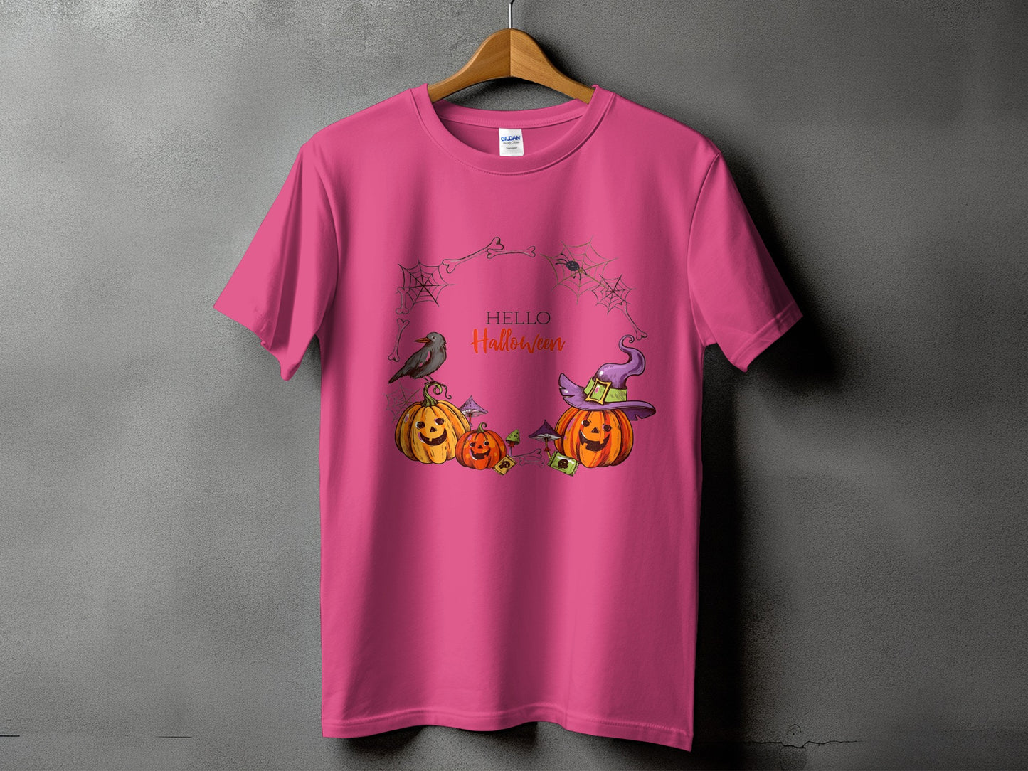 Pink t-shirt with Halloween-themed graphic featuring pumpkins, a crow, and text.