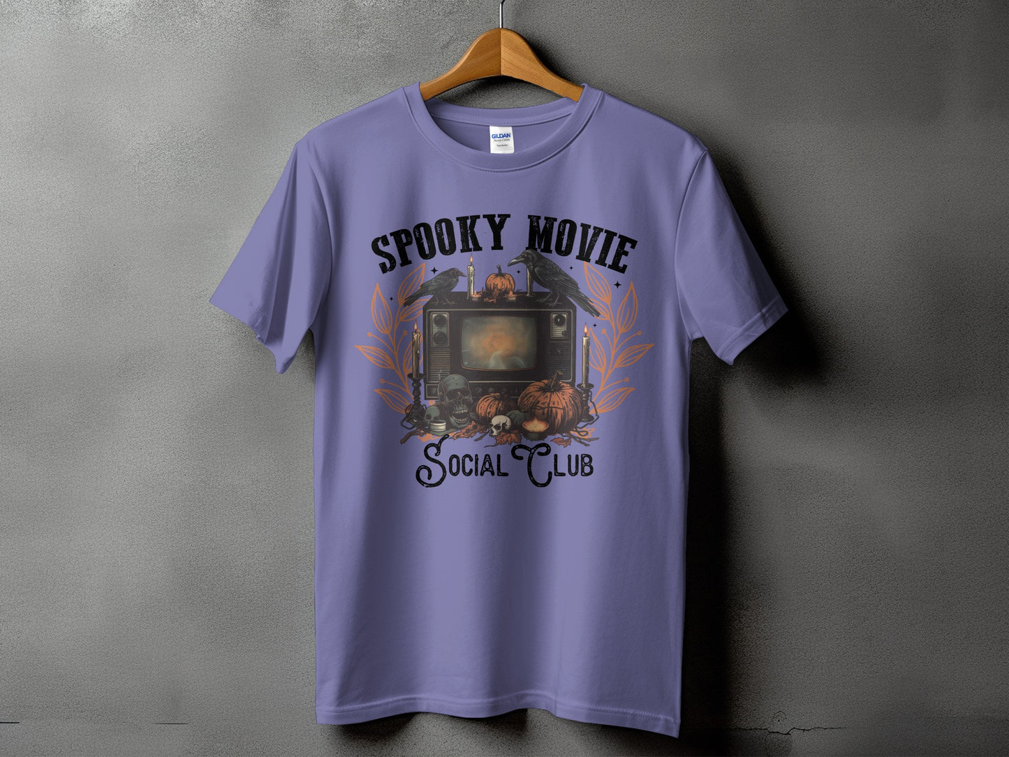 Purple t-shirt with "Spooky Movie Social Club" graphic featuring a retro TV, crows, skulls, and pumpkins.