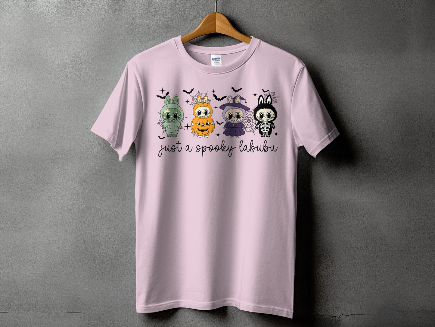 Pink t-shirt with four cute Halloween characters and "just a spooky labubu" text.