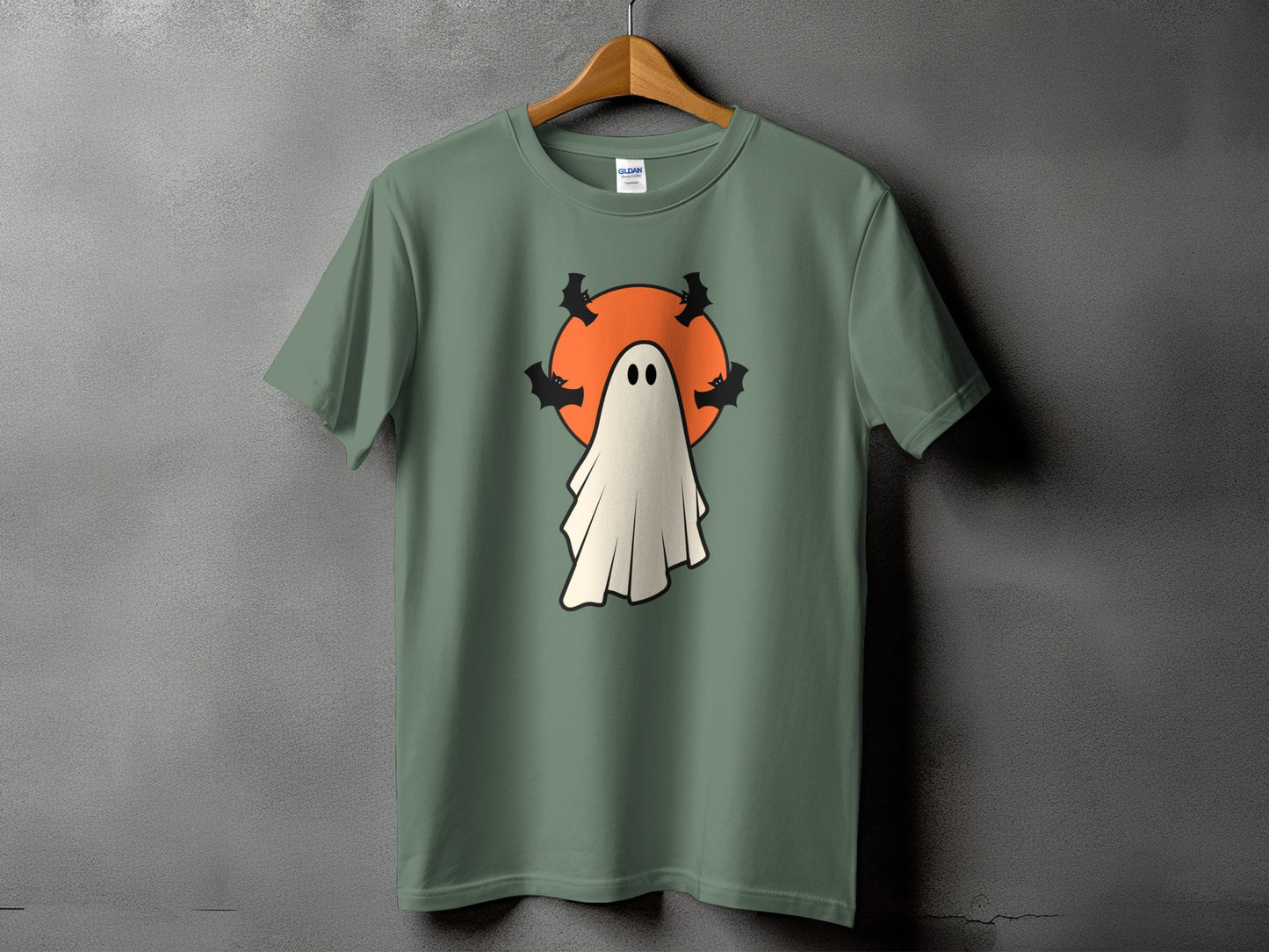Green t-shirt with a cartoon ghost and bats against an orange circle.