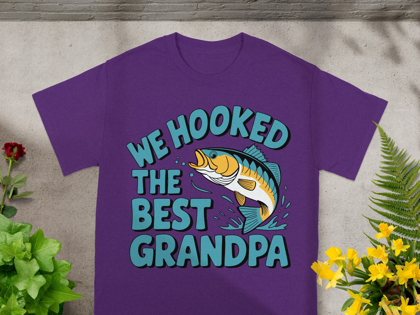 Purple t-shirt with text "WE HOOKED THE BEST GRANDPA" and a jumping fish graphic.