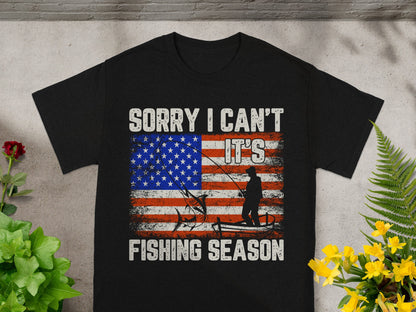 Black t-shirt with distressed American flag, fishing silhouette, and text "Sorry I Can't It's Fishing Season".