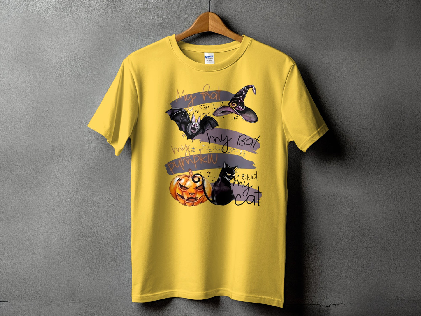 Yellow t-shirt with Halloween graphic: bat, witch hat, pumpkin, and cat with text.