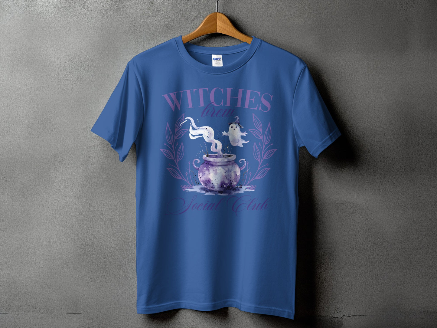 Blue t-shirt with "Witches Brew Social Club" text and watercolor cauldron, ghosts, and floral wreath.