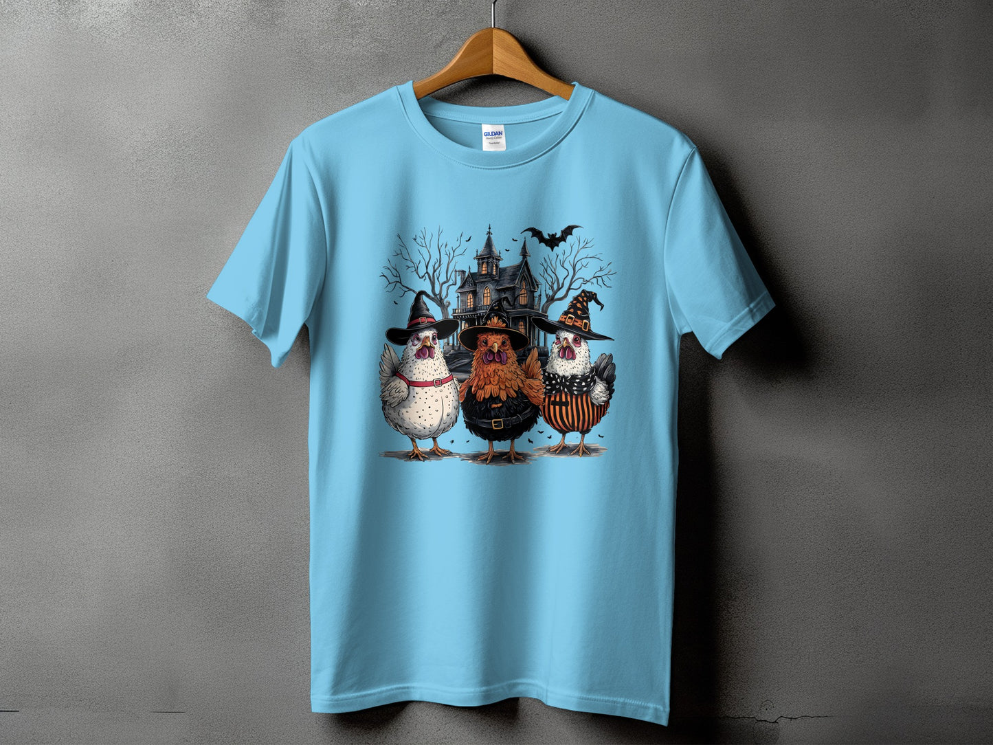 Light blue t-shirt with three chickens in witch hats and costumes.