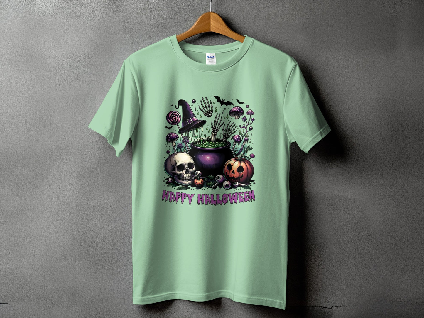 Green t-shirt with Halloween graphic featuring cauldron, skull, pumpkin, and text.