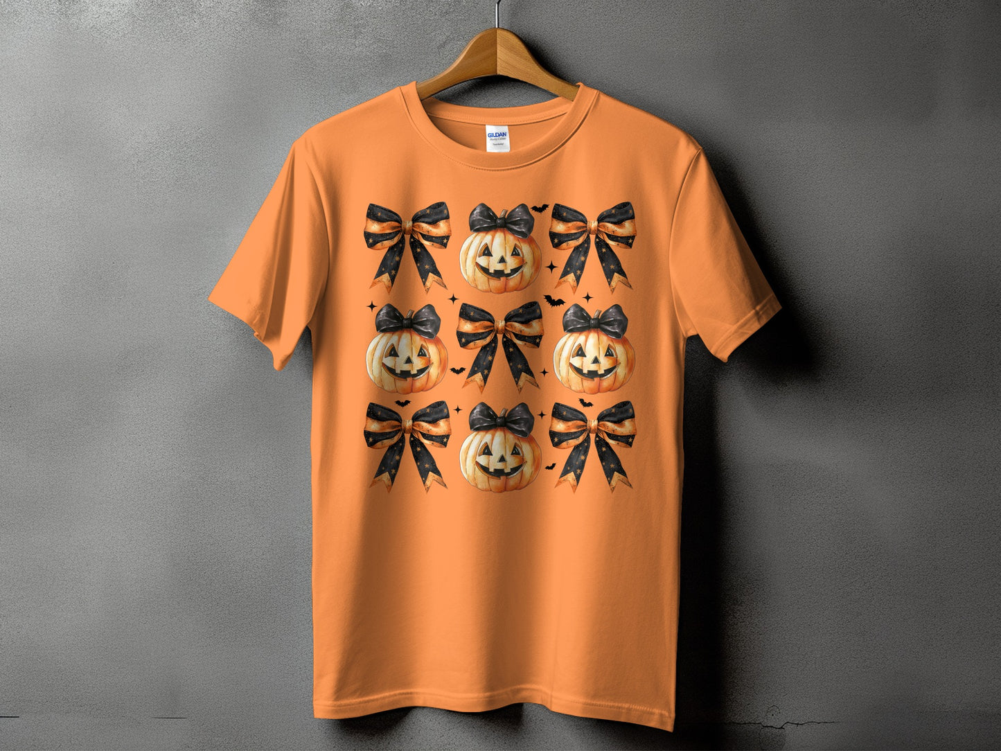 Orange t-shirt with a pattern of smiling pumpkins and black and orange striped bows.