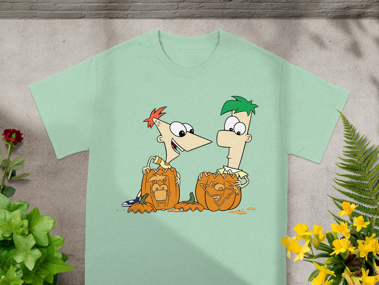Phineas and Ferb carved pumpkins with their faces on a mint green t-shirt.