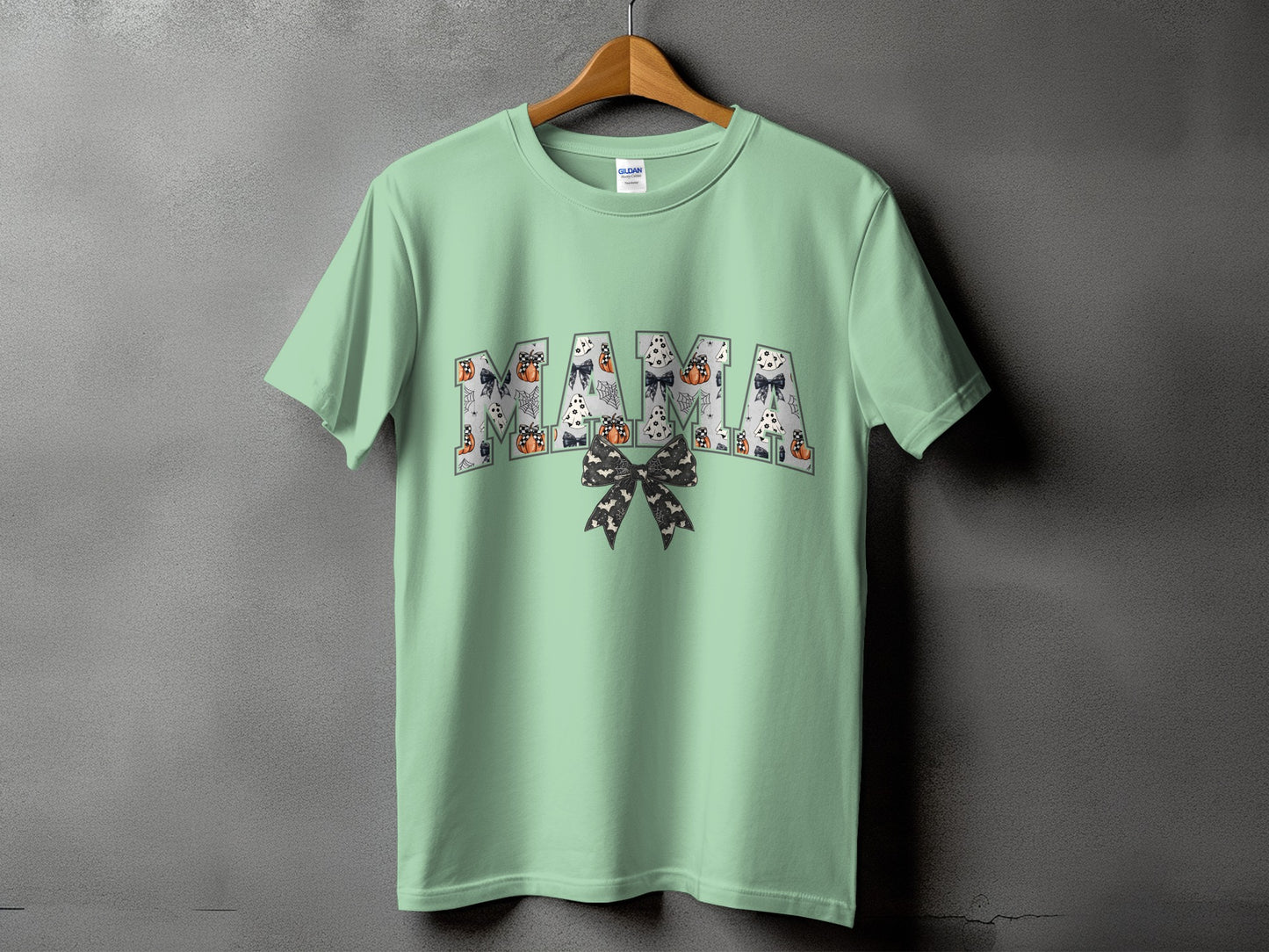 Mint green t-shirt with "Mama" text in a Halloween pattern of ghosts and pumpkins.