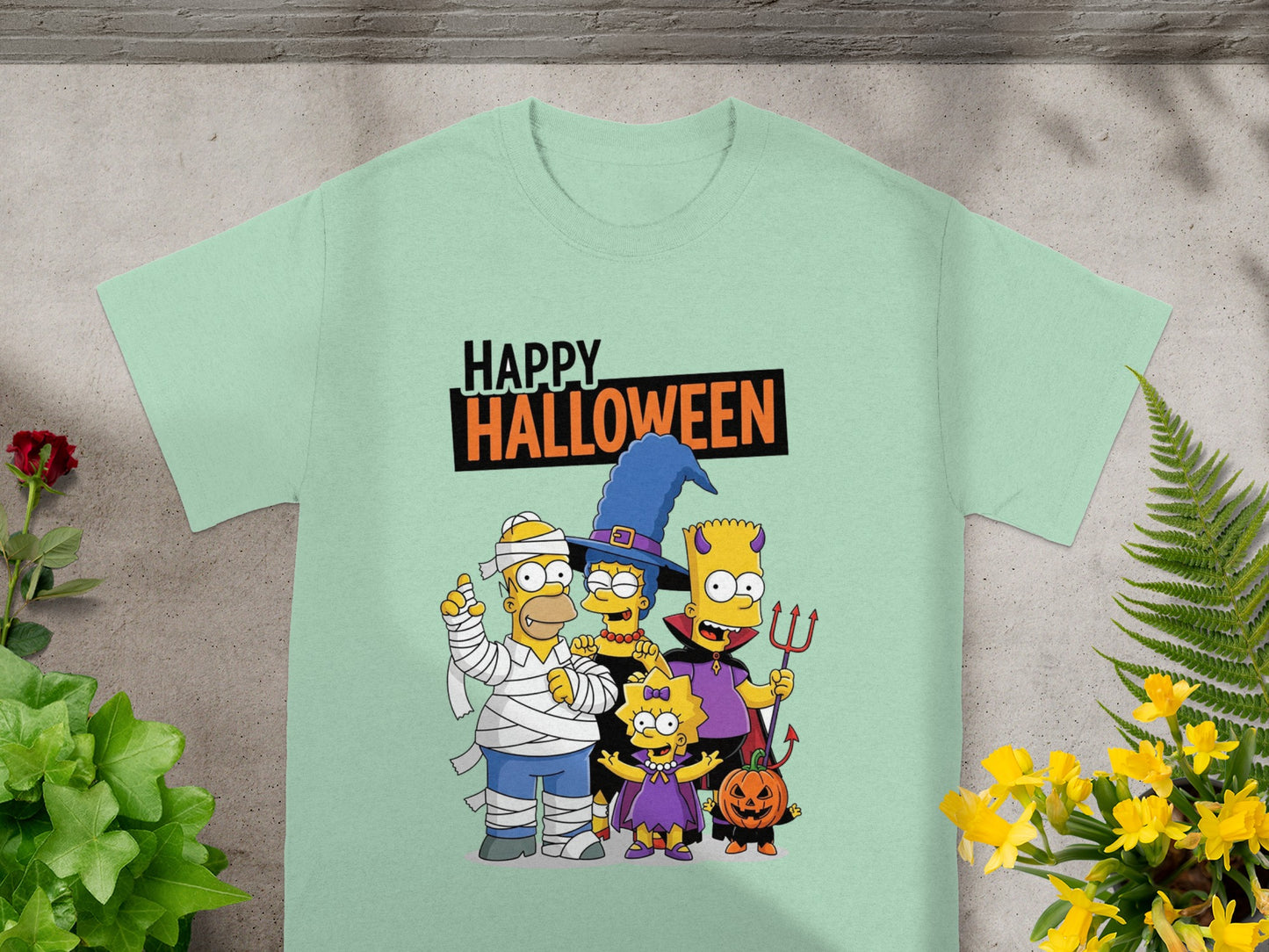 The Simpsons family in Halloween costumes with "HAPPY HALLOWEEN" text on a light mint t-shirt.