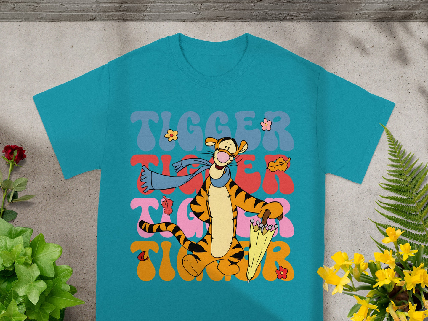 Tigger character with umbrella and leaves on teal t-shirt.