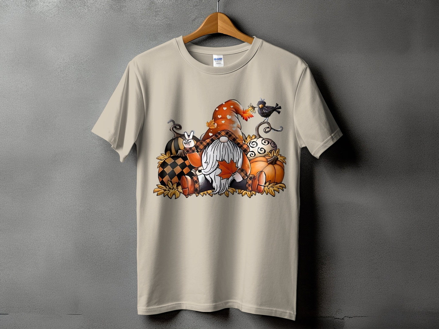 Gnome with pumpkins and fall leaves graphic on a cream t-shirt.