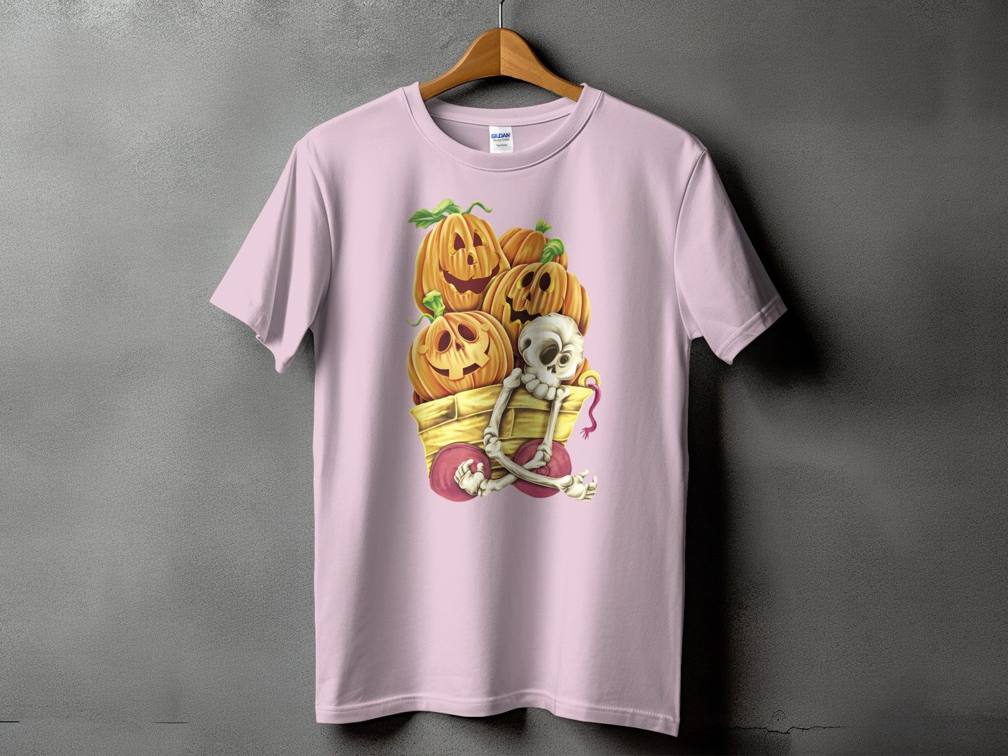 Pink t-shirt with Halloween graphic of pumpkins and skeleton in a wagon.