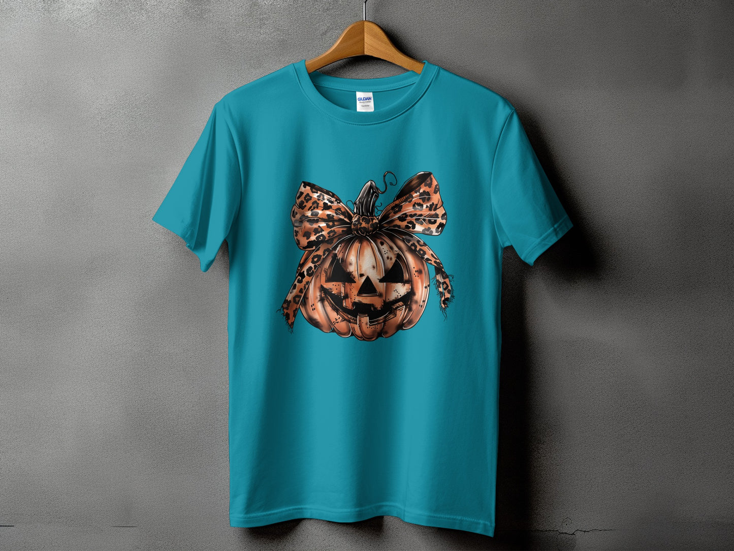 Teal t-shirt featuring a jack-o'-lantern with a leopard print bow.