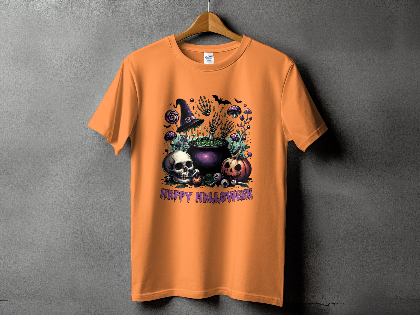 Orange t-shirt with a Halloween graphic featuring a cauldron, skull, pumpkin, and text.