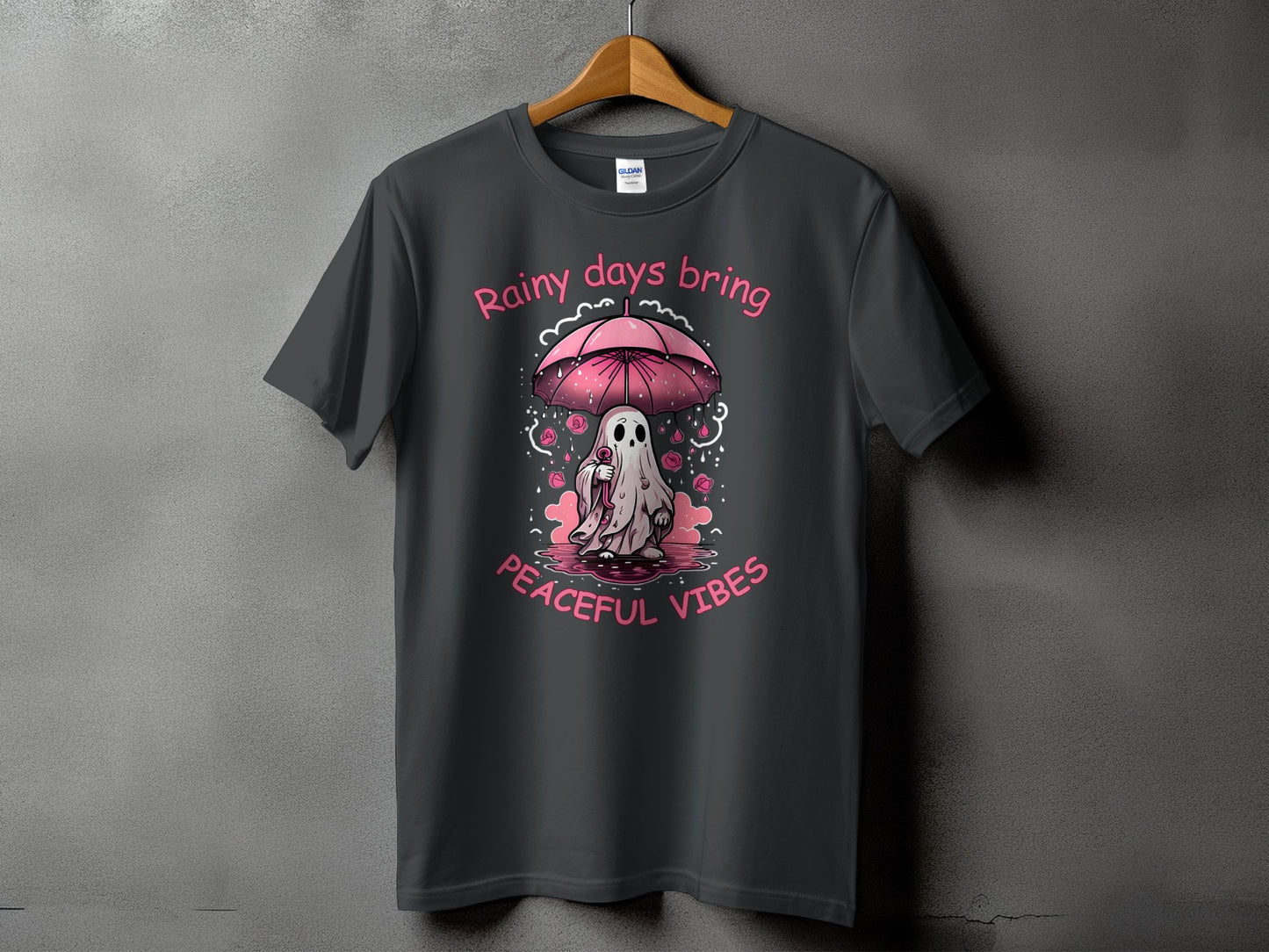 Dark gray t-shirt with pink text "Rainy days bring peaceful vibes" and a ghost under an umbrella.