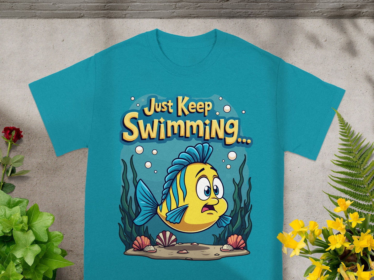 Teal t-shirt with yellow cartoon fish and "Just Keep Swimming..." text.
