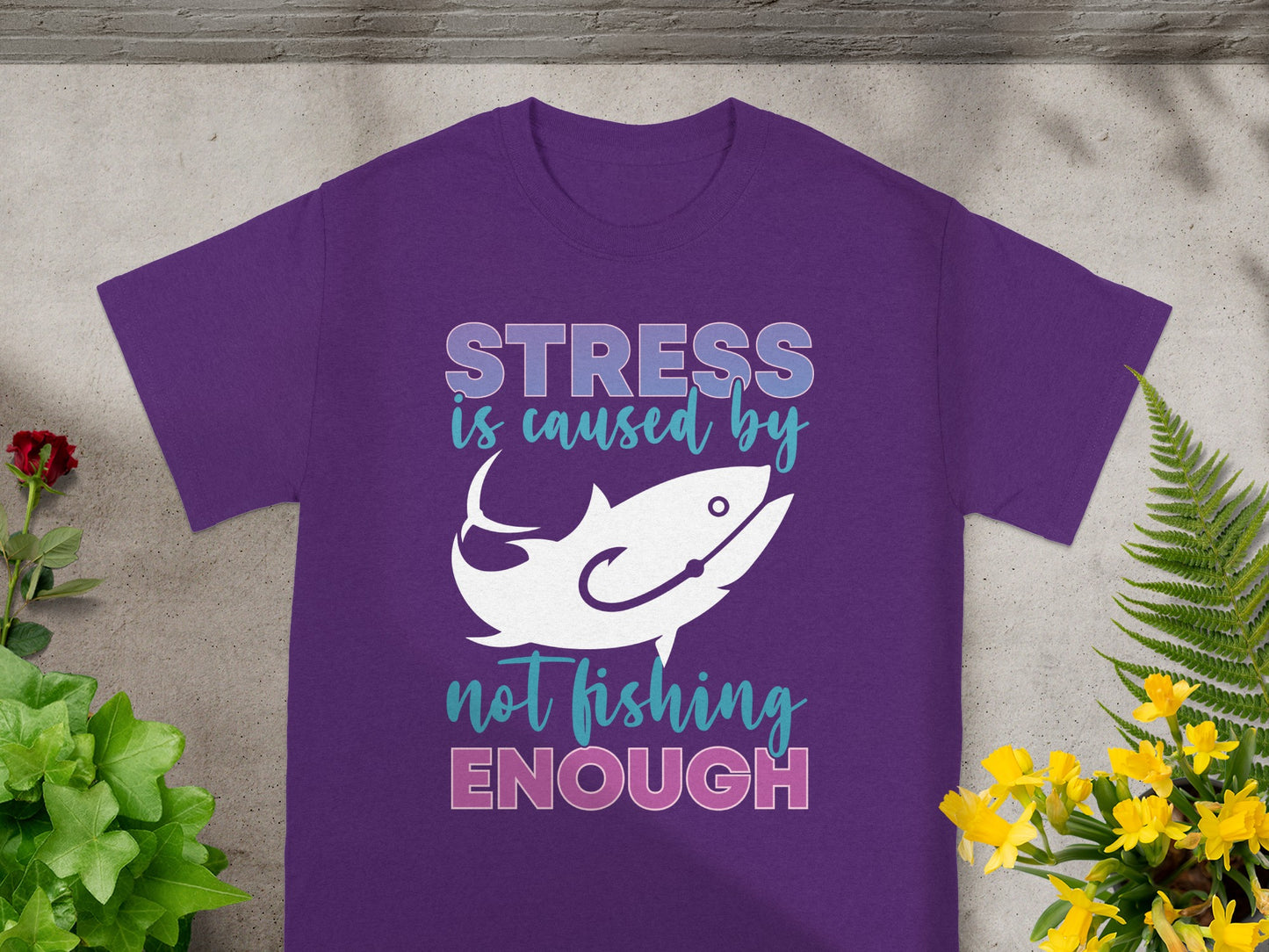 Purple t-shirt with text "STRESS is caused by not fishing ENOUGH" and a fish graphic.