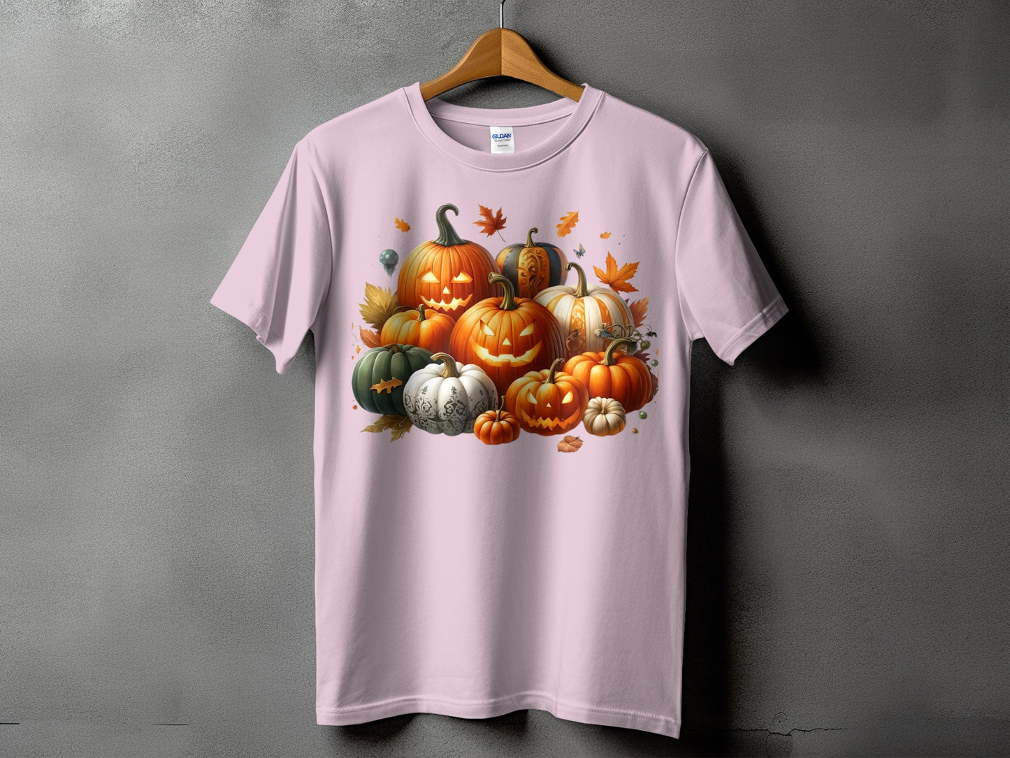 Pink t-shirt with a graphic of a variety of carved and uncarved pumpkins and autumn leaves.