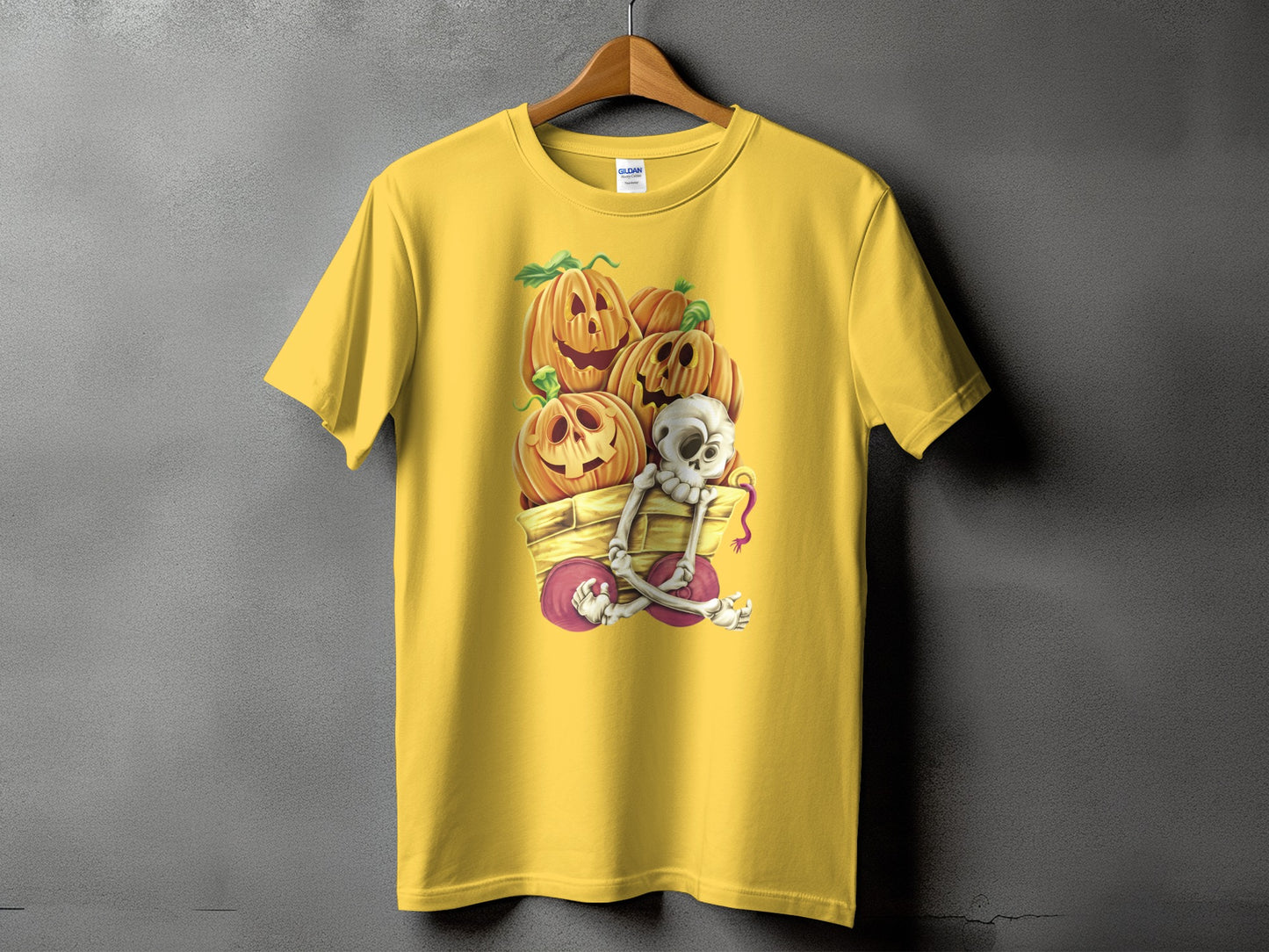 Yellow t-shirt with pumpkins and a skeleton in a wagon Halloween graphic.