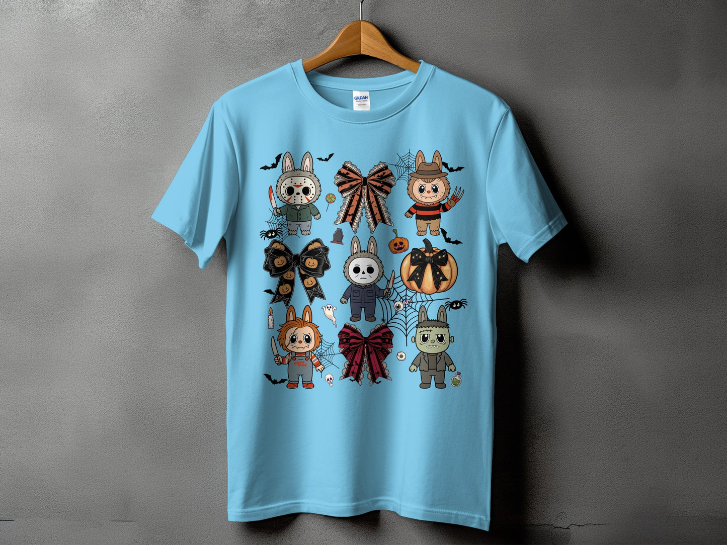 Light blue t-shirt with a collage of cute horror-themed cartoon characters and Halloween decorations.