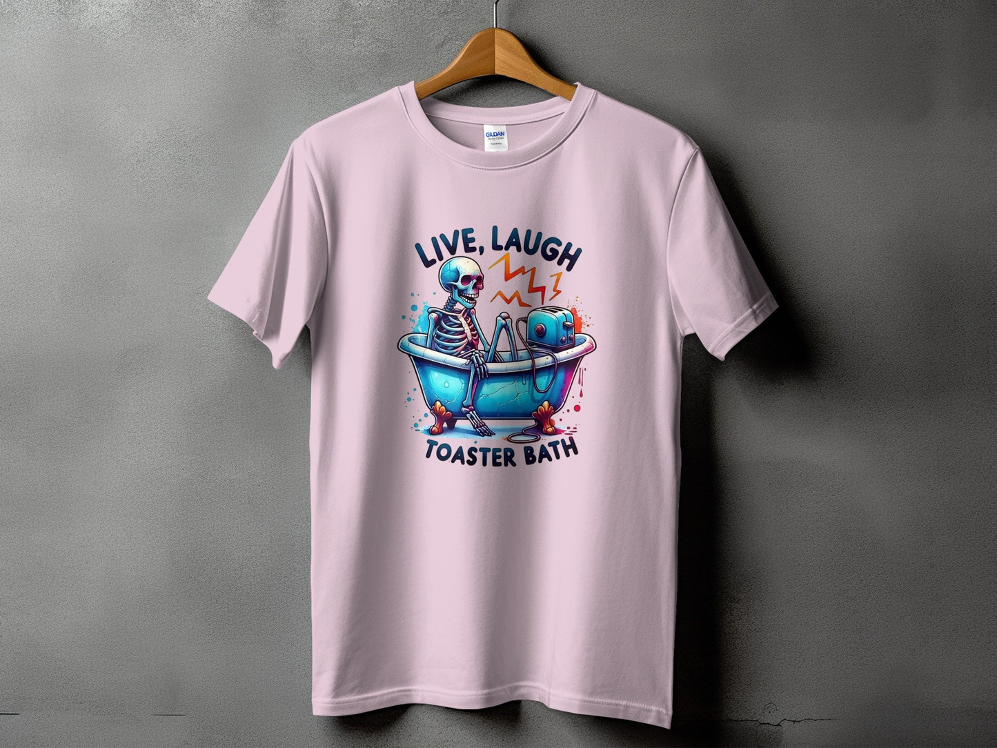 Pink t-shirt with skeleton in bathtub and toaster, text "LIVE, LAUGH TOASTER BATH".