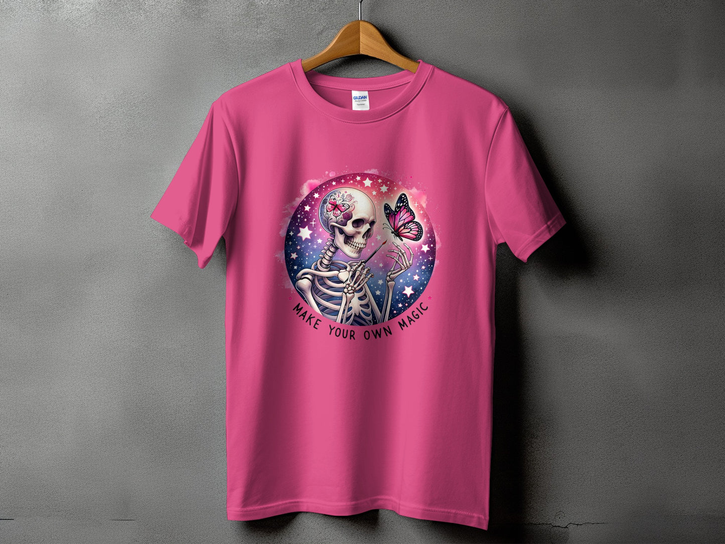 Pink t-shirt with skeleton graphic and text "MAKE YOUR OWN MAGIC".