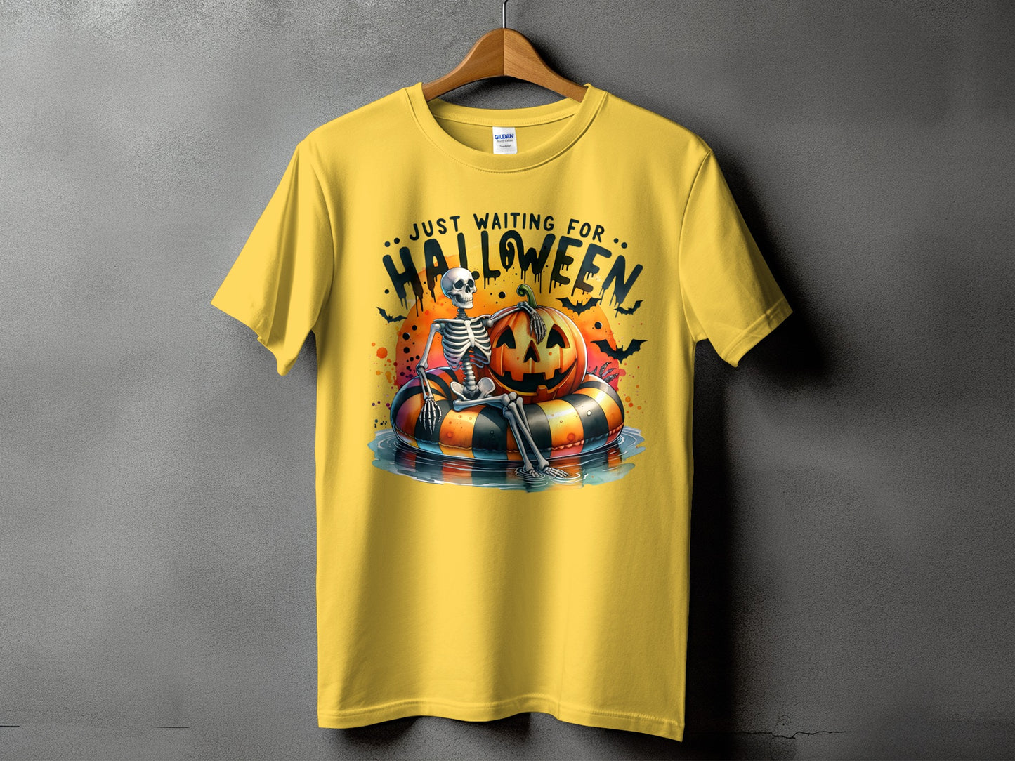Yellow t-shirt with skeleton on a pumpkin float and text "JUST WAITING FOR HALLOWEEN".