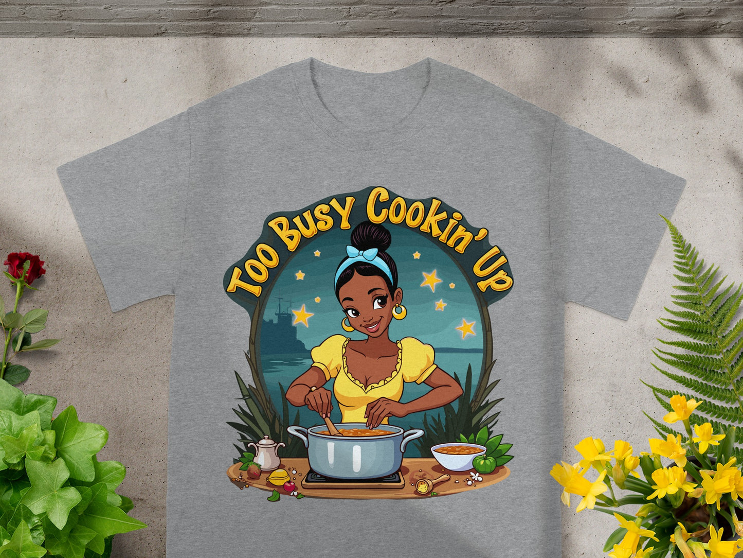 T-shirt graphic with cartoon woman cooking and text "Too Busy Cookin' Up".