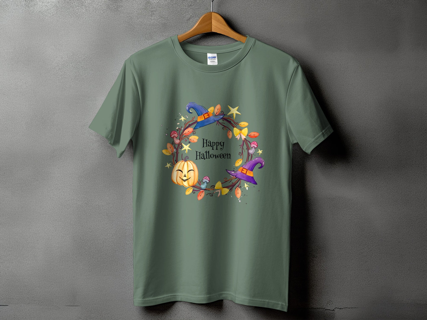 Green t-shirt with a Halloween wreath featuring a smiling pumpkin, witch hats, and leaves.