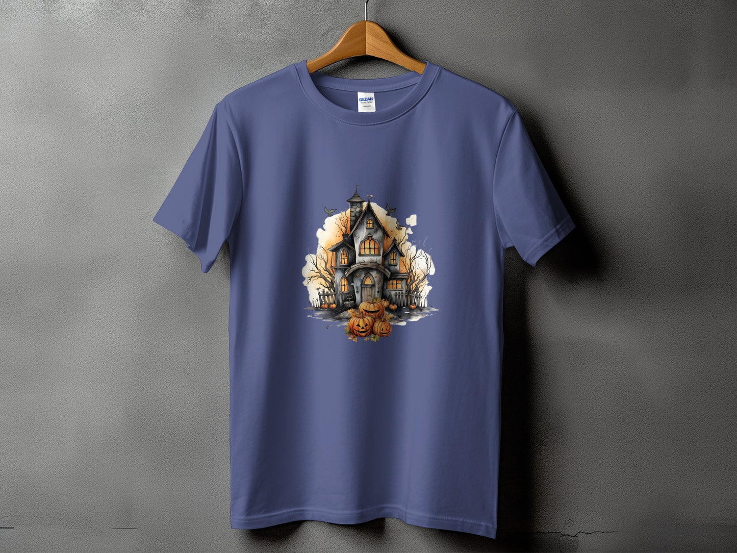 Purple t-shirt with a watercolor-style Halloween haunted house and pumpkins graphic.