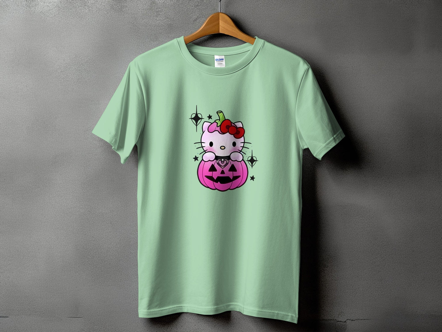 Light green t-shirt with Hello Kitty sitting in a pink pumpkin with a red bow.